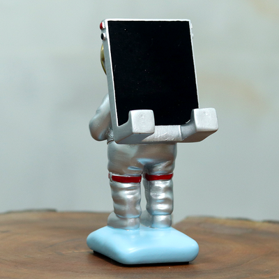Astronaut inspired mobile phone stand where the phone acts as an oxygen cylinder of the astronaut.