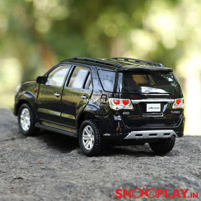 The black coloured toy car Fortuner , that comes with a complimentary jute pouch, and is perfect for decor purposes.