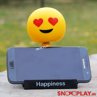 Emoji bobblehead with heart eyes holding a phone in its mobile stand.